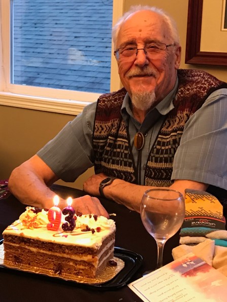 Man with birthday cake topped with candles in the shape of 93.