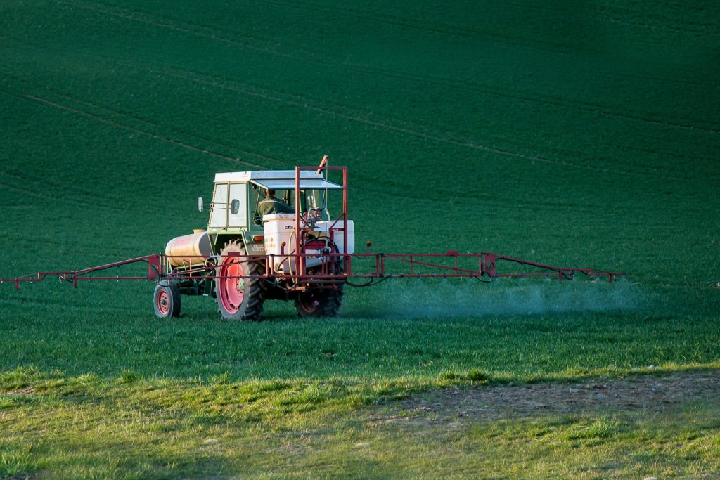 Tractor spraying pesticide onto field